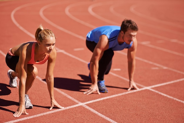 Vou levá-lo na foto de dois jovens se preparando para correr em uma pista de atletismo