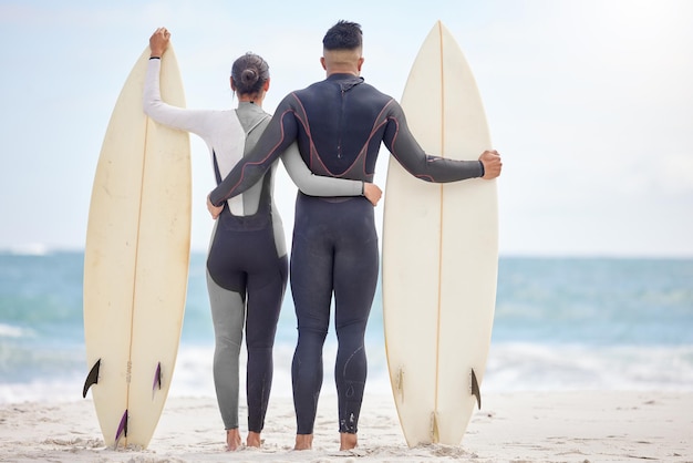 Vou pegar todas as ondas com você foto de um jovem casal segurando pranchas de surf na praia