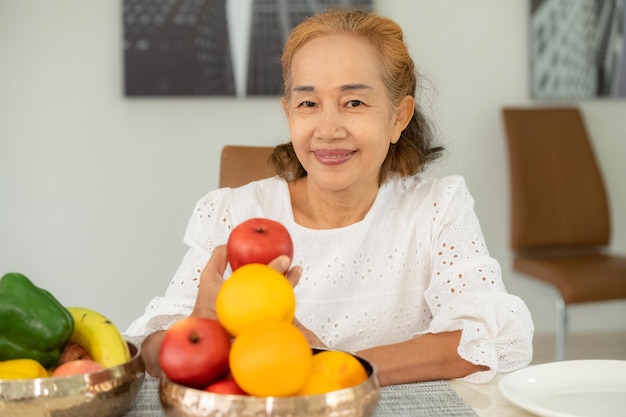 Vovó asiática feliz come frutas em casa