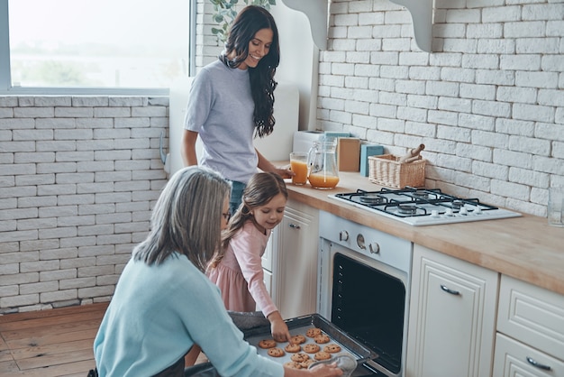 Vovó linda tirando biscoitos do forno e sorrindo enquanto passa um tempo com a família