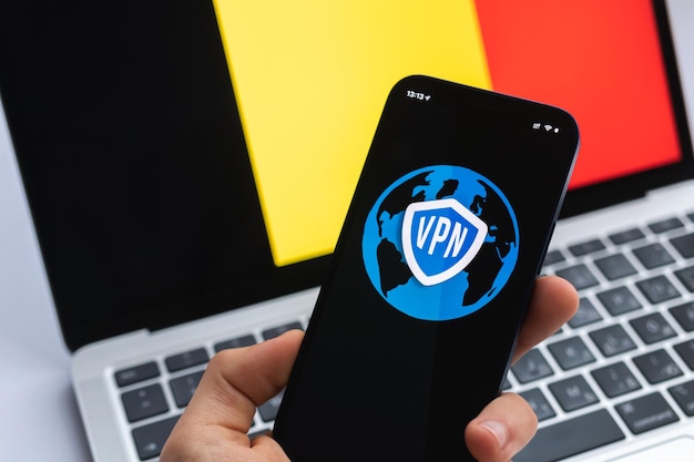 VPN en Bélgica Concepto de Internet seguro y seguro Privacidad Mano con teléfono móvil y aplicación VPN Bandera y computadora portátil en la foto de fondo