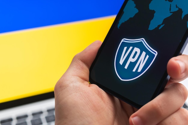 VPN in der Ukraine Sicheres und sicheres Internetkonzept Datenschutz Hand mit Mobiltelefon und VPN-Anwendung Flagge und Laptop auf dem Hintergrundfoto