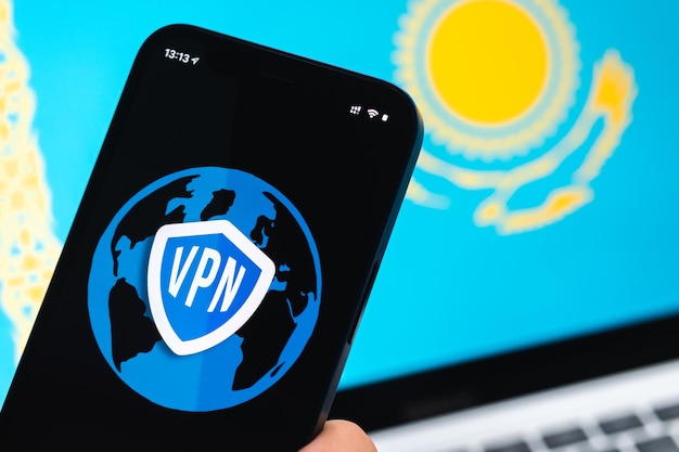 VPN en Kazajstán Concepto de Internet seguro y seguro Privacidad Mano con teléfono móvil y aplicación VPN Bandera y computadora portátil en la foto de fondo