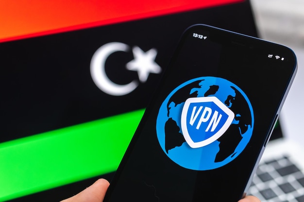 VPN na Líbia Conceito de internet seguro e seguro Privacidade Mão com celular e aplicativo VPN Bandeira e laptop na foto de fundo