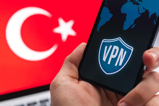 VPN na Turquia Conceito de internet seguro e seguro Privacidade Mão com celular e aplicativo VPN Bandeira e laptop na foto de fundo