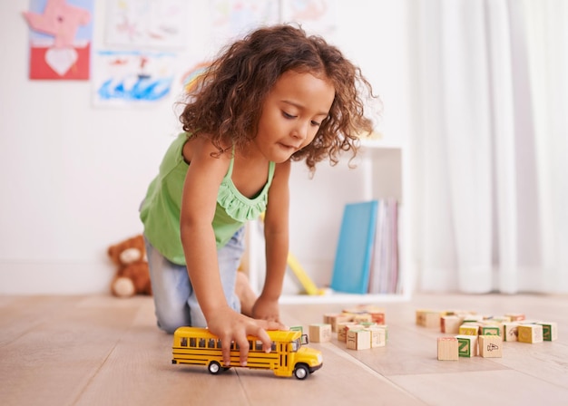 Vroom vai ao ônibus escolar Foto de uma garotinha brincando com um caminhão de brinquedo e blocos de construção