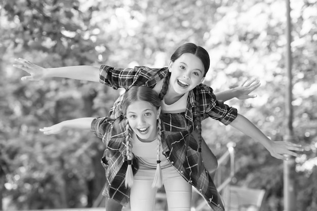 Vuela conmigo retrato de hermanas felices niños pequeños niñas en camisa Dos jóvenes hipster divertidas en ropa de verano de moda niños despreocupados posando al aire libre Modelos positivos Traje casual de hipsters