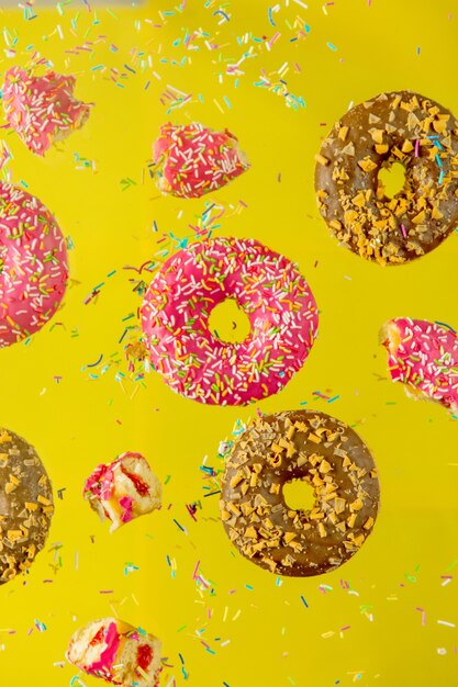 Vuela en donas de cereza y chocolate con cobertura sobre una superficie amarilla.