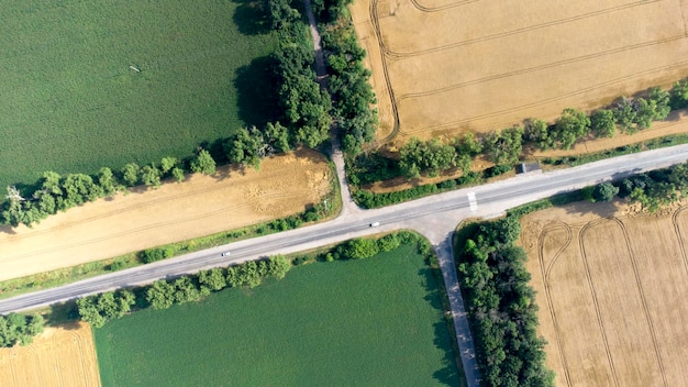 Vuelo aéreo con drones sobre una carretera asfaltada entre amarillo y verde