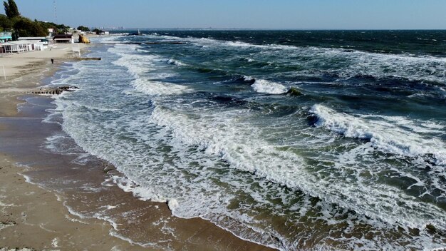 Vuelo aéreo con drones sobre las olas del mar que ruedan hacia la orilla arenosa