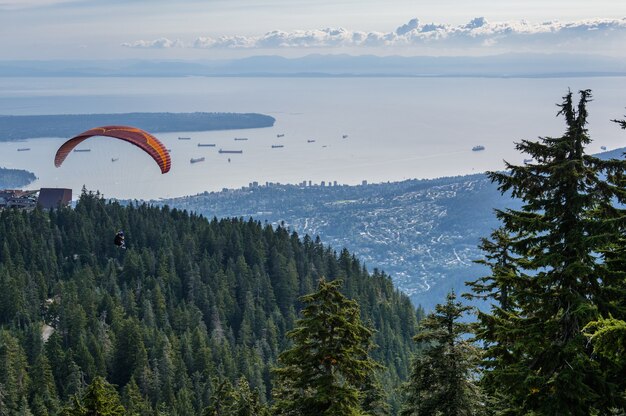 Vuelo en parapente en tándem con deslizamiento azul y bonitas nubes termales esponjosas en el fondo. Tema de deportes al aire libre y extremos.