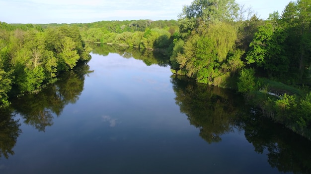 Vuelo de vista aérea drone sobre la superficie lisa del espejo del río y árboles con vegetación brillante a lo largo de bankson soleado día tranquilo. Fondo natural, entorno natural. Ecología, protección del medio ambiente.