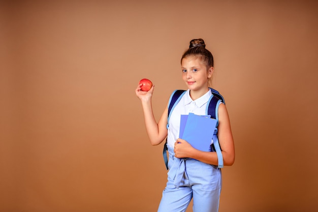 De vuelta a la escuela. alegre niña feliz con una mochila azul con manzana