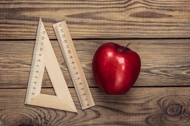 De vuelta a la escuela. Apple con reglas sobre una mesa de madera