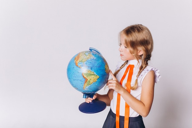 De vuelta a la escuela. Cute adorable blondie caucásica chica con globo en uniforme escolar sobre fondo blanco.