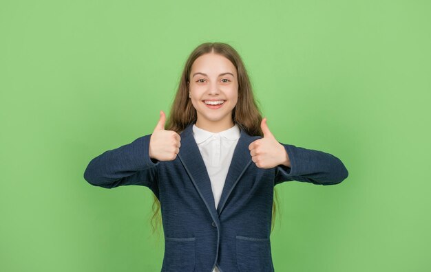 De vuelta a la escuela. día del conocimiento. educación Infantil. niño en uniforme. 1 de septiembre. Niño sobre fondo verde mostrando el pulgar hacia arriba. expresar emociones. alegre chica adolescente.