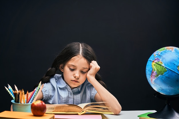 De vuelta a la escuela. estudiante guapo concentrado leyendo un libro sentado en la mesa.