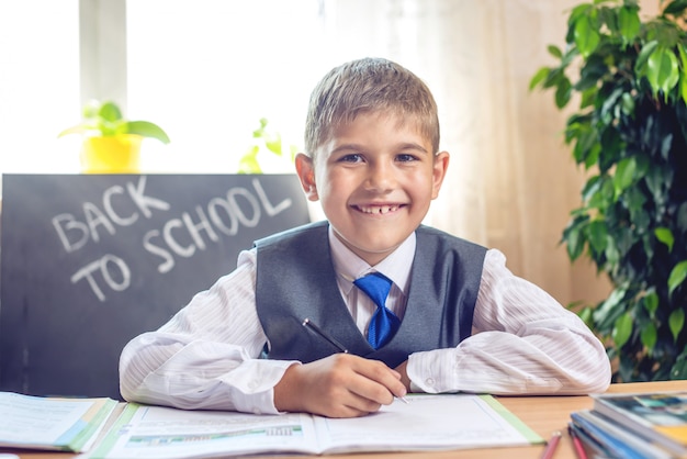 De vuelta a la escuela. Lindo niño sentado en el escritorio en el aula.