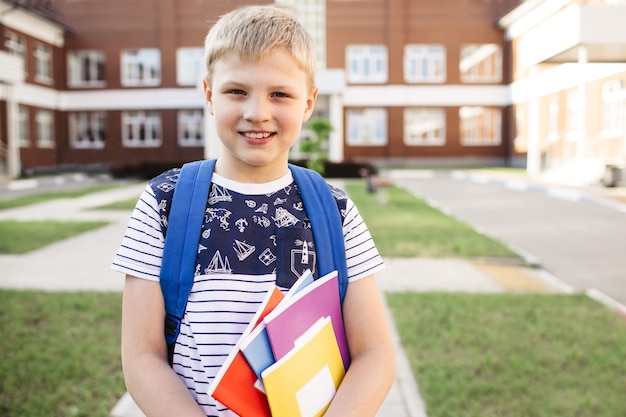 De vuelta a la escuela. Niño de escuela sonriente de la escuela primaria con cuadernos y mochila. Educación. Día de los conocimientos.