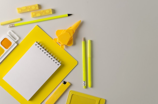 De vuelta a la escuela. La tendencia es amarilla sobre gris. Material escolar sobre un fondo gris. Lápices, gomas de borrar, cuadernos, tintes, sacapuntas plano - artículos para la oficina de color amarillo.