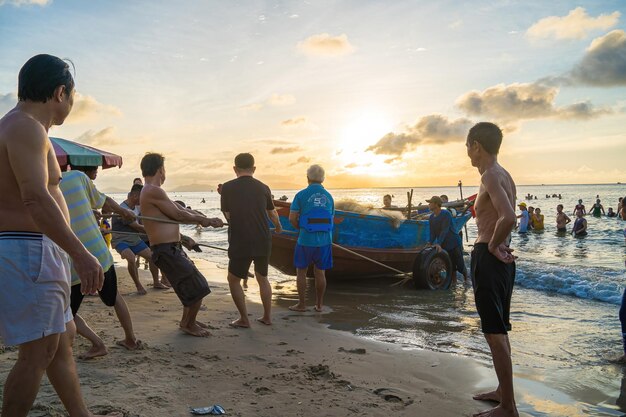 Vung Tau VIETNÃ 20 DE AGOSTO 2022 Pescador lançando sua rede ao nascer ou pôr do sol Pescadores tradicionais preparam a rede de pesca Pescadores na praia na Pesca