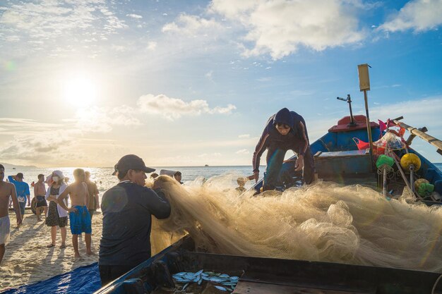 Vung Tau VIETNAM 20. AUG 2022 Fischer wirft sein Netz bei Sonnenaufgang oder Sonnenuntergang Traditionelle Fischer bereiten das Fischernetz vor Fischer am Strand beim Angeln