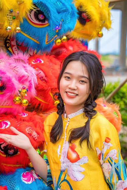 Vung Tau VIETNAM 7 DE ENERO DE 2023 Niña sonriente y de pie cerca del espectáculo de danza del león en el festival de año nuevo chino Festival Tet Danza del león Espectáculos callejeros de danza del dragón y danza del león en Vietnam