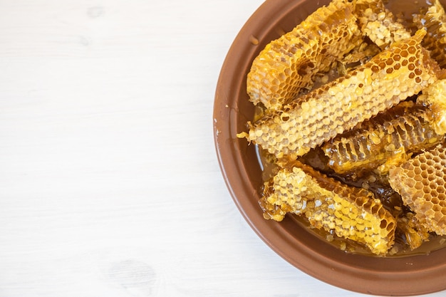 Waben in weißer Platte auf dem Holztisch. Natürliches Bio-Bienenprodukt. Gesunder Lebensstil.