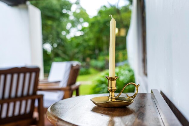 Wachskerze in einem vergoldeten Leuchter auf einem Holztisch auf der Terrasse des Hauses