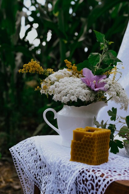 Wachskerze mit rustikalen Blumen auf Holztisch