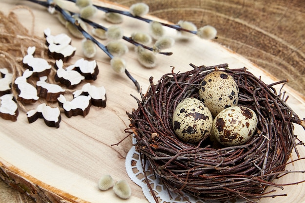 Wachteleier in einem Nest, Holzhasen und Weidenkätzchenzweige mit Knospen