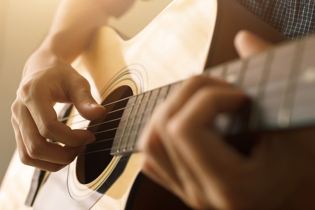 Wählen Sie Fokus und Weichzeichner, die Hand des Mannes spielt Akustikgitarre, musikalisches Konzept