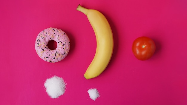 Wählen Sie gesunde Früchte anstelle von ungesunden Süßigkeiten mit viel Zucker - rosa Hintergrund