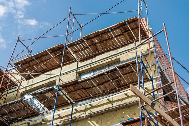 Wärmedämmung eines roten Backsteinhauses mit Mineralwolle. Die Verwendung von Gerüsten beim Bau eines Hauses.