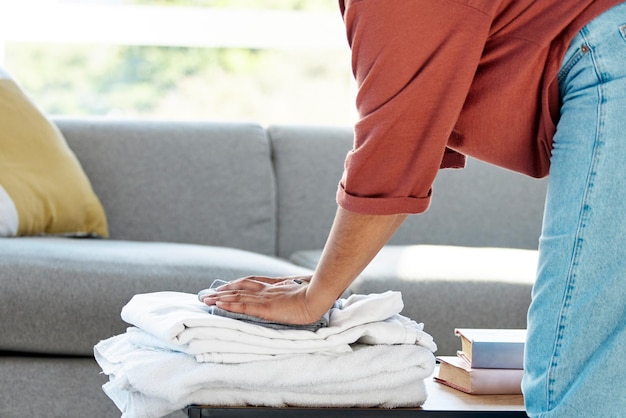 Wäschearbeiten und Hände einer Frau mit Kleidung reinigen Handtücher und Kleidung aus der Wäsche im Wohnzimmer Frühjahrsputz und Reiniger mit Waschhaufen Hausarbeit und Haushalt