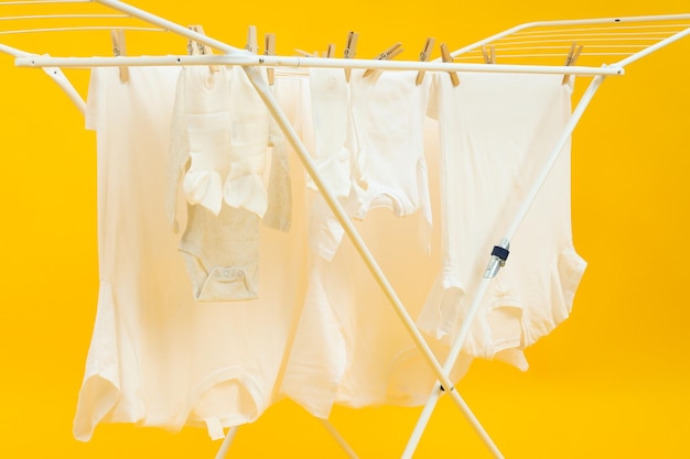 Wäscheständer mit verschiedenen Kleidungsstücken auf gelbem Hintergrund