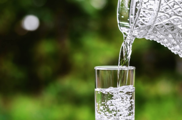 Wässern Sie in Glas auf grünem Naturhintergrund