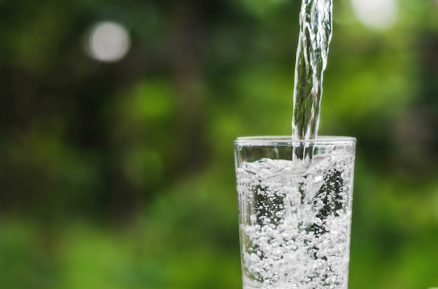 Wässern Sie in Glas auf grünem Naturhintergrund