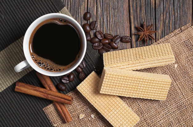 Wafers deliciosos e uma xícara de café quente no café da manhã em uma mesa de madeira rústica
