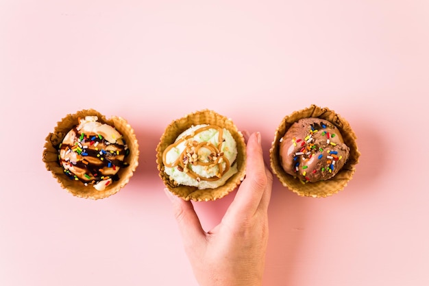 Waffel-Eisbecher mit Eiskugeln auf rosa Hintergrund.