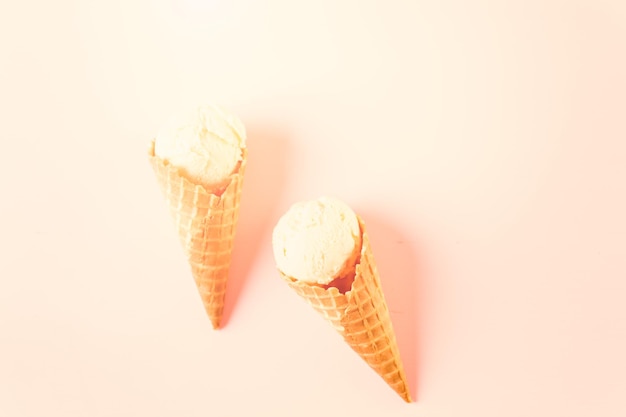 Waffel-Eistüten mit Teller mit Eiskugeln auf rosa Hintergrund.