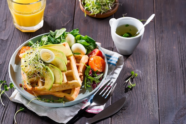 Waffel mit Salat, Ei, Saft und Avocados zum Frühstück