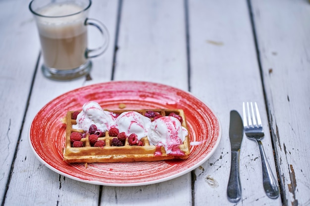 Foto waffeles con frutos rojos y helado en una mesa de madera. enfoque selectivo.