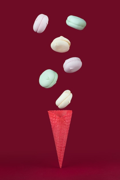 Waffelhorn mit farbigem Marshmallow sieht aus wie Makronen auf einem rosa Pastellhintergrund. Draufsicht, Süßigkeiten und Süßigkeitenkonzept.