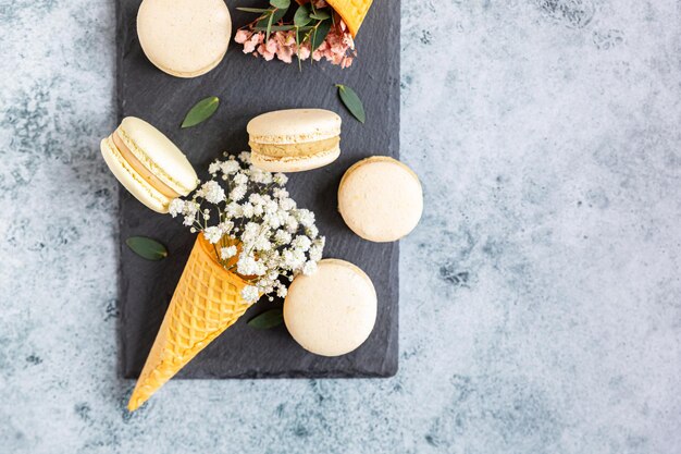 Waffelkegel gefüllt mit Gypsophila-Blüten und Macarons mit Blättern Pastellfarben