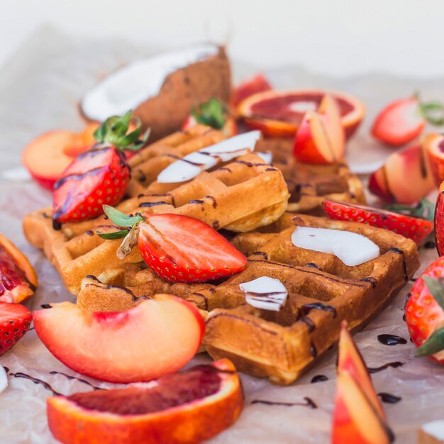 Waffeln mit Erdbeeren, Kokosnuss, Pflaume und Orange mit Schokolade