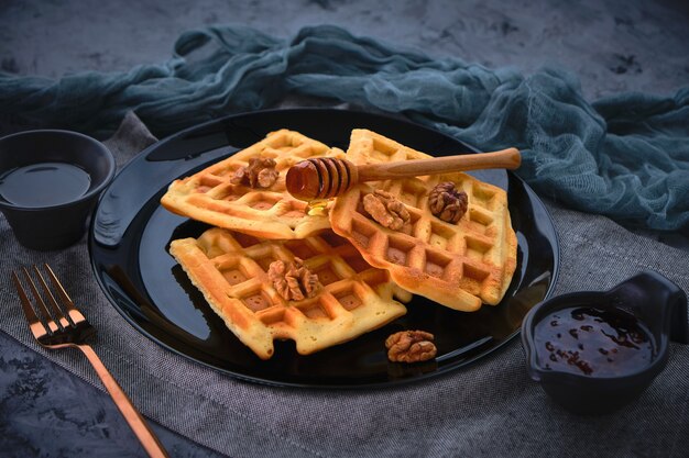 Waffeln mit Honig auf einer dunklen Oberfläche, Nahaufnahme