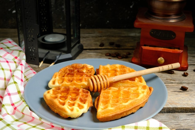 Waffeln süßes Gebäck auf Teller vor Hintergrund Kaffeemühle und dekorative Lampe mit Kerze