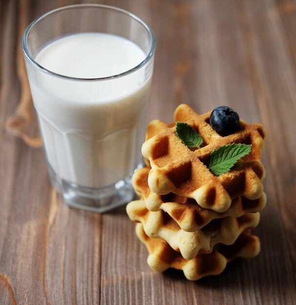 Waffeln und Glas mit Milch Morgenfrühstück auf Holzbackgro