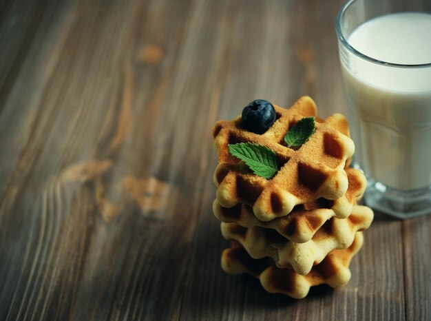 Waffeln und Glas mit Milch Morgenfrühstück auf Holzhintergrund